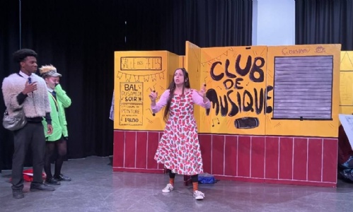 Two students performing on stage with French actress
